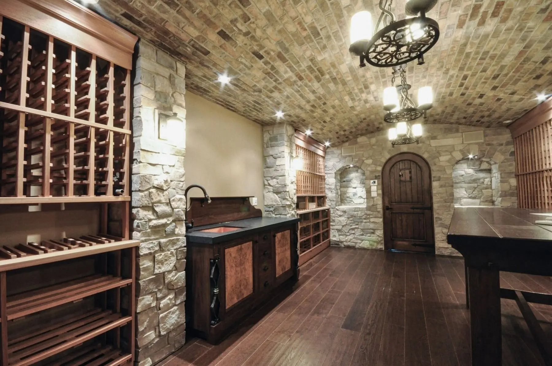 Custom wine cellar with stone walls and wooden wine racks, designed by Homestead Woodworks for optimal wine storage and aesthetic appeal